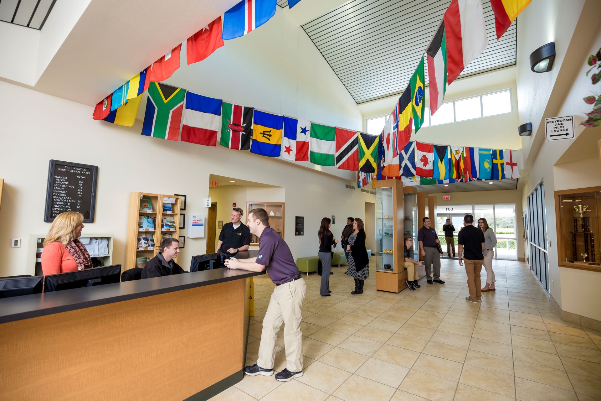Reception area with flags of different countries hanging from the ceiling, staff and visitors interacting